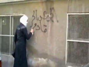 Une jeune révolutionnaire syrienne fait des graffitis sur les murs de Damas « l'armée syrienne libre arrive ».